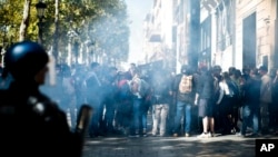 Demonstran berlindung dari gas air mata yang ditembakkan oleh polisi anti huru hara saat demonstrasi rompi kuning, di Paris, Sabtu, 21 September 2019. (Foto: AP/Kamil Zihnioglu)