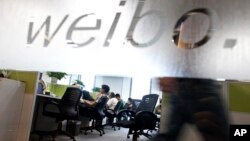 FILE - Employees work at their desks at a Sina Weibo office in Beijing, China, Aug. 1, 2012. Launched in 2009, the Twitter-like microblog site, has been a digital megaphone for millions of Chinese to voice their views on a variety of issues, including a new quiz show critics say is laced with propaganda.