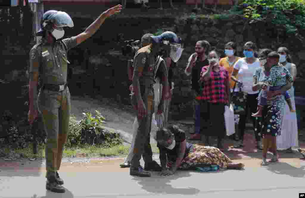 Seorang anggota keluarga narapidana memohon-mohon kepada petugas sambil bersimpuh di kaki seorang polisi, meminta informasi mengenai kondisi kerabatnya yang ditahan di penjara Mahara, pinggiran Kolombo, Sri Lanka. (Foto: AP)&nbsp;