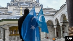 A protester from the Uyghur community living in Turkey stands with flags in the Beyazit mosque during a protest against the visit of China's Foreign Minister to Turkey, in Istanbul on March 25, 2021. 