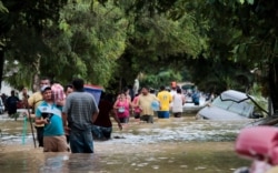 FILE - Residents walk past inundated vehicles in the flooded streets of Planeta, Honduras, Nov. 6, 2020, in the aftermath of Hurricane Eta.