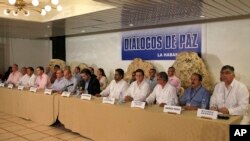 Representatives from Colombia's government negotiation team, left of center, and representatives from the Revolutionary Armed Forces of Colombia, or FARC, negotiation team, right side of table, issue a joint statement in front of a sign that reads in Span