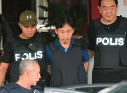 북한 김정남 암살 사건 용의자로 말레이시아 경찰에 체포됐던 리정철(가운데)이 2017년 3월 쿠알라룸푸르 세팡 경찰서에서 방탄조끼를 입은 채 공항으로 향하는 차에 오르고 있다. 리정철은 이 날 북한으로 추방됐다.