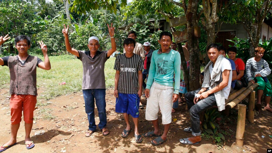 Warga desa mengacungkan tanda perdamaian saat militer Filipina datang di pinggiran kota Marawi, Filipina selatan, Selasa (30/5). 