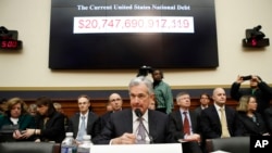 The national debt is shown behind Federal Reserve Chairman Jerome Powell as arrives to testify on the semiannual monetary policy report to the House Financial Services Committee, Tuesday, Feb. 27, 2018, in Washington.