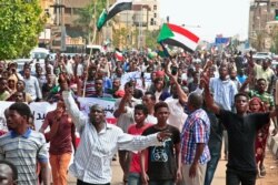 People wave the old and current flags of Sudan as they chant slogans during a mass demonstration near the presidential palace in Sudan's capital, Khartoum, Sept. 12, 2019.