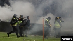 Petugas polisi anti huru hara menembakkan gas air mata setelah pertandingan sepak bola antara Arema vs Persebaya yang berakhir dengan kerusuhan di Stadion Kanjuruhan, Malang 2 Oktober 2022. 