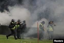 Seorang petugas polisi anti-huruhara menembakkan gas air mata setelah pertandingan sepak bola antara Arema vs Persebaya di Stadion Kanjuruhan di Malang. (Foto: Antara via Reuters)