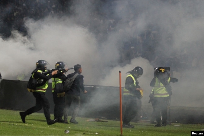 Seorang petugas polisi anti-huruhara menembakkan gas air mata setelah pertandingan sepak bola antara Arema vs Persebaya di Stadion Kanjuruhan di Malang. (Foto: Antara via Reuters)