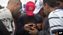 FILE - Migrants heading for Austria consult a map on a cell phone, in Budapest, Hungary, Sept. 5, 2015.