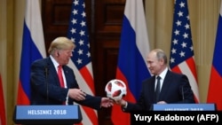 FINLAND -- Russia's President Vladimir Putin (R) offers a ball of the 2018 football World Cup to US President Donald Trump during a joint press conference after a meeting at the Presidential Palace in Helsinki, on July 16, 2018.