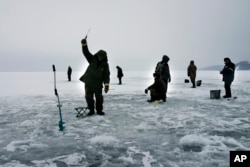 FILE - Ukrainians fish on the thin ice surface of a waterway on the Kiev Reservoir on the Dnipro River on a warm winter's day in the village of Stari Petrivtsi outside Kyiv, Ukraine, Thursday, Jan. 9, 2016.