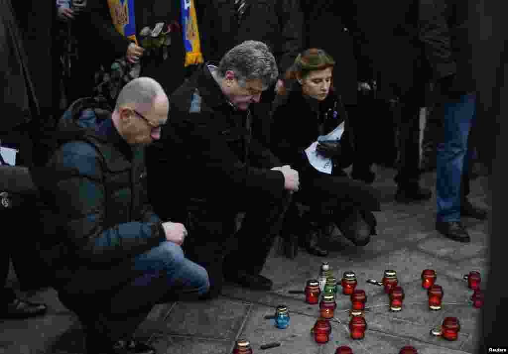 Ukraine's President Petro Poroshenko (center), his wife Marina and Prime Minister Arseny Yatseniuk (left) light candles during a peace march in Kyiv for the victims on a passenger bus which came under fire near the town of Volnovakha in eastern Ukraine, Jan. 18, 2015.
