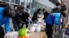 北京街頭的快遞員把消費者購買的食品放在居民樓外的長椅上。 （2022年3月16日）