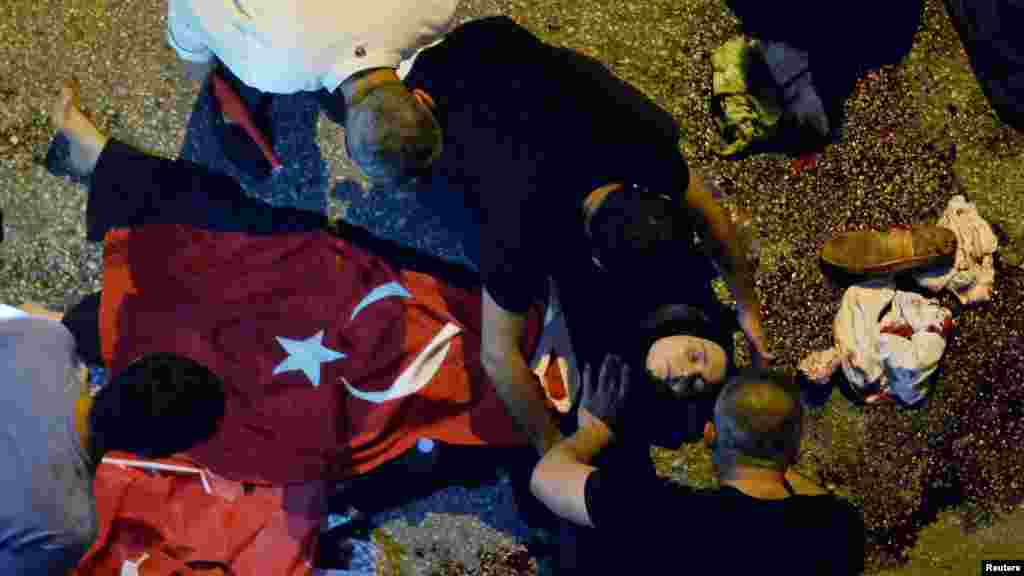 Des manifestants administrent des premiers soins à une femme blessée couverte d&rsquo;un drapeau turc près de l&lsquo;état-major de l&rsquo;armée à Ankara, Turquie, 16 juillet 2016. &nbsp;