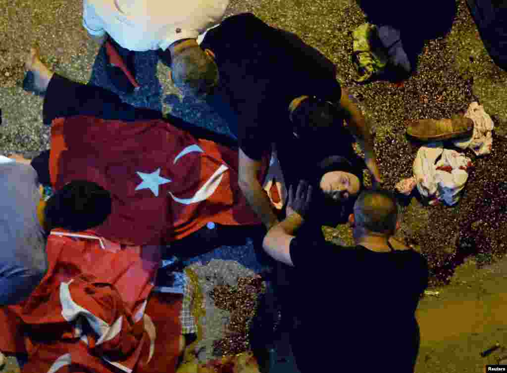 An injured woman draped in a Turkish flag is checked by others near military headquarters in Ankara, Turkey, July 16, 2016.