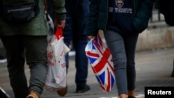 FILE - People carry shopping bags in London, Britain, Dec. 27, 2018.