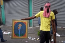 A man poses with a painting after looting a shop during a protest to demand the resignation of president Jovenel Moise in Port-au-Prince, Haiti, Sept. 27, 2019.