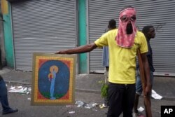 A man poses with a painting after looting a shop during a protest to demand the resignation of president Jovenel Moise in Port-au-Prince, Haiti, Sept. 27, 2019.