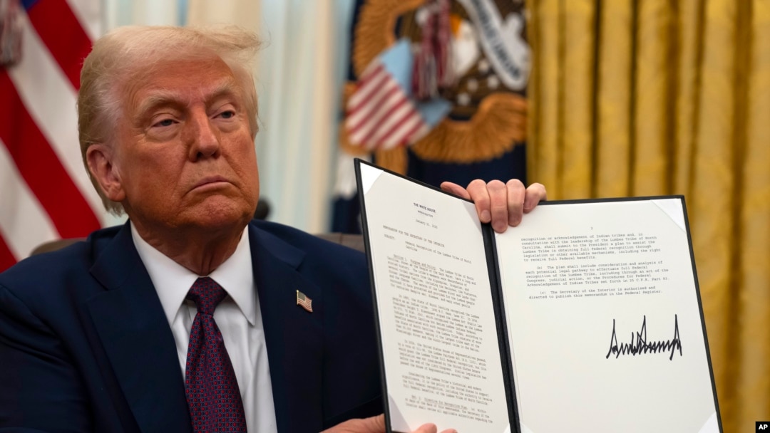 Predsjednik Donald Trump drži potpisanu izvršnu naredbu koja se odnosi na pleme Lumbee iz Sjeverne Karoline u Ovalnoj kancelariji Bijele kuće, u četvrtak, 23. januara 2025., u Washingtonu. (AP Photo/Ben Curtis)