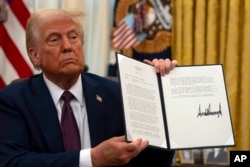 U.S. President Donald Trump holds a signed executive order relating to the Lumbee Tribe of North Carolina at the White House on Jan. 23, 2025, in Washington.