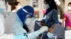 FILE - A medical worker collects a swab sample from a Top Glove worker to be tested for the COVID-19 outside a hostel under enhanced lockdown in Klang, Malaysia, Nov. 18, 2020. 