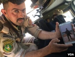 Gunner Ali el-Babli shows a photo of himself after a recent battle, in Mosul, Iraq, May 4, 2017. (H. Murdock/VOA)
