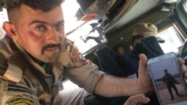 Gunner Ali el-Babli shows a photo of himself after a recent battle, in Mosul, Iraq, May 4, 2017. (H. Murdock/VOA)