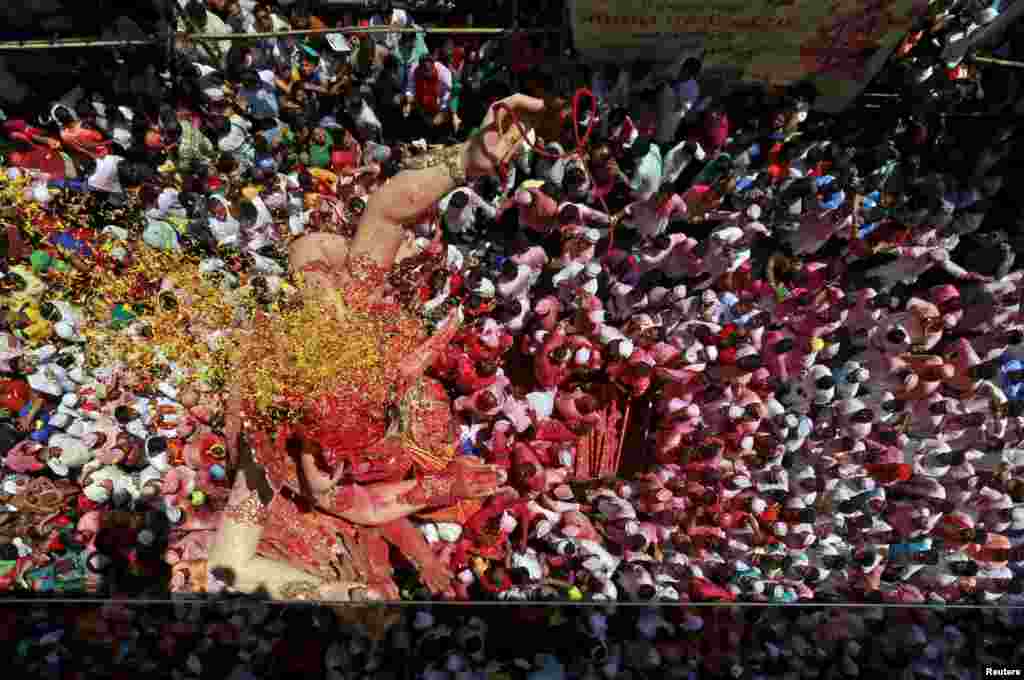 An idol of Hindu god Ganesh, the deity of prosperity, is showered with colored powder and flowers as it is taken through a street on the last day of the ten-day-long Ganesh Chaturthi festival in Mumbai, India.