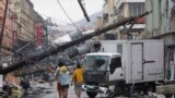 Survivors walk under a fallen electric post after super Typhoon Haiyan battered Tacloban city, central Philippines. 