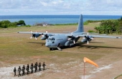 Philippine troops march toward a Philippine Air Force C-130 transport plane that sits on the Thitu Island tarmac, April 21, 2017.