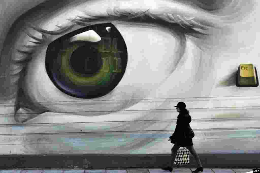 A woman passes by a graffiti in central Athens. Germany and Greece faced off in yet another eurozone meeting Friday in search of a last minute bailout compromise, with Berlin insisting Athens accept continued austerity in return for fresh debt aid.