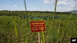 A warning sign stands in a field contaminated with dioxin near Danang airport, during a ceremony marking the start of a cleanup project at a former U.S. military base in Danang, Vietnam, August 9, 2012.