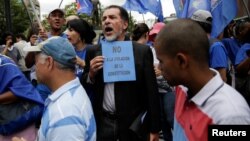 An opposition supporter holds a placard that reads "No to the violation of the constitution" during a gathering to demand a referendum to remove Venezuela's President Nicolas Maduro in Caracas, Venezuela, Sept. 7, 2016.