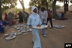 Plates of food are brought to Cameroonian refugees who are gathering in N'djamena, Chad, Dec. 10, 2021.