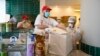 Para pekerja di sebuah toko pizza menyiapkan pesanan untuk 'home delivery' di kota Naples, Italia, Senin (27/4). 