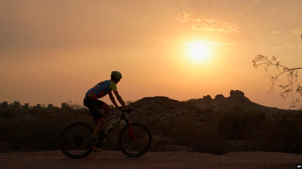Um ciclista passa de bicicleta pelo pôr do sol no Parque Papago durante uma onda de calor onde as temperaturas chegam a 46 graus Celsius na terça-feira, 15 de junho de 2021, em Phoenix.  (AP Photo / Ross D. Franklin)