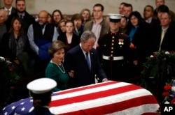 Former President George W. Bush and former first lady Laura Bush stand at the flag-draped casket of former President George H.W. Bush as he lies in state in the Capitol's Rotunda in Washington, Dec. 4, 2018.