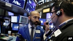 FILE - Specialist Fabian Caceres (L) and trader Michael Capolino confer on the floor of the New York Stock Exchange, Aug. 14, 2018.