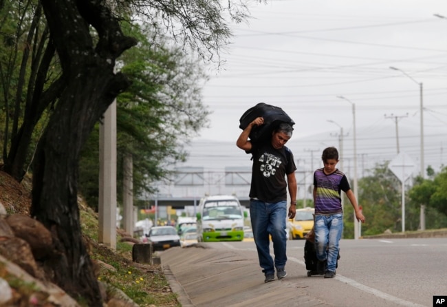 En esta foto del 28 de junio de 2018, el padre venezolano Darwin Zapata camina con su hijo de 12 años por una carretera en Cúcuta, Colombia, mientras se dirigen a Perú.