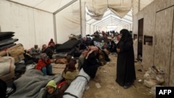 FILE - Displaced people gather inside a tent in the al-Hol camp in northeastern Syria, Dec. 8, 2018. 