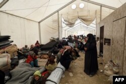 FILE - Displaced people gather inside a tent in the al-Hol camp in northeastern Syria, Dec. 8, 2018.