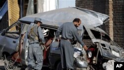 Afghan police officials investigate a damaged vehicle at the site of an explosion in Jalalabad, Nangarhar province east of Kabul, Afghanistan. At least three policemen were killed and six others injured in a bomb explosion, police officials said, April 21