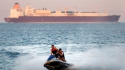 In this Friday, July 26, 2019 file photo, a ship crosses the Gulf of Suez towards the Red Sea as holiday-makers ride a jet ski at al Sokhna beach in Suez, 127 kilometers (79 miles) east of Cairo, Egypt. (AP Photo/Amr Nabil)