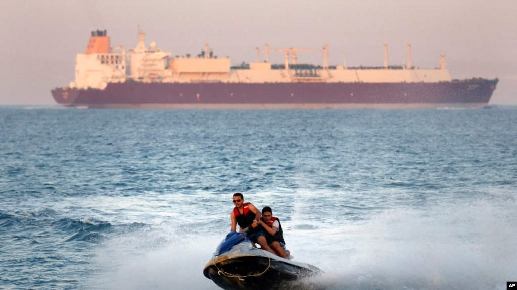 In this Friday, July 26, 2019 file photo, a ship crosses the Gulf of Suez towards the Red Sea as holiday-makers ride a jet ski at al Sokhna beach in Suez, 127 kilometers (79 miles) east of Cairo, Egypt. (AP Photo/Amr Nabil)