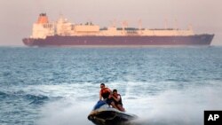 In this Friday, July 26, 2019 file photo, a ship crosses the Gulf of Suez towards the Red Sea as holiday-makers ride a jet ski at al Sokhna beach in Suez, 127 kilometers (79 miles) east of Cairo, Egypt. (AP Photo/Amr Nabil)