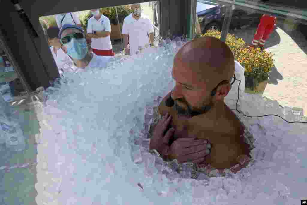 Austrian ice swimmer Josef Koeberl is standing in a glass cabin filled with ice to break the world record for a human to stay side an ice box in Melk, Sept. 5, 2020.