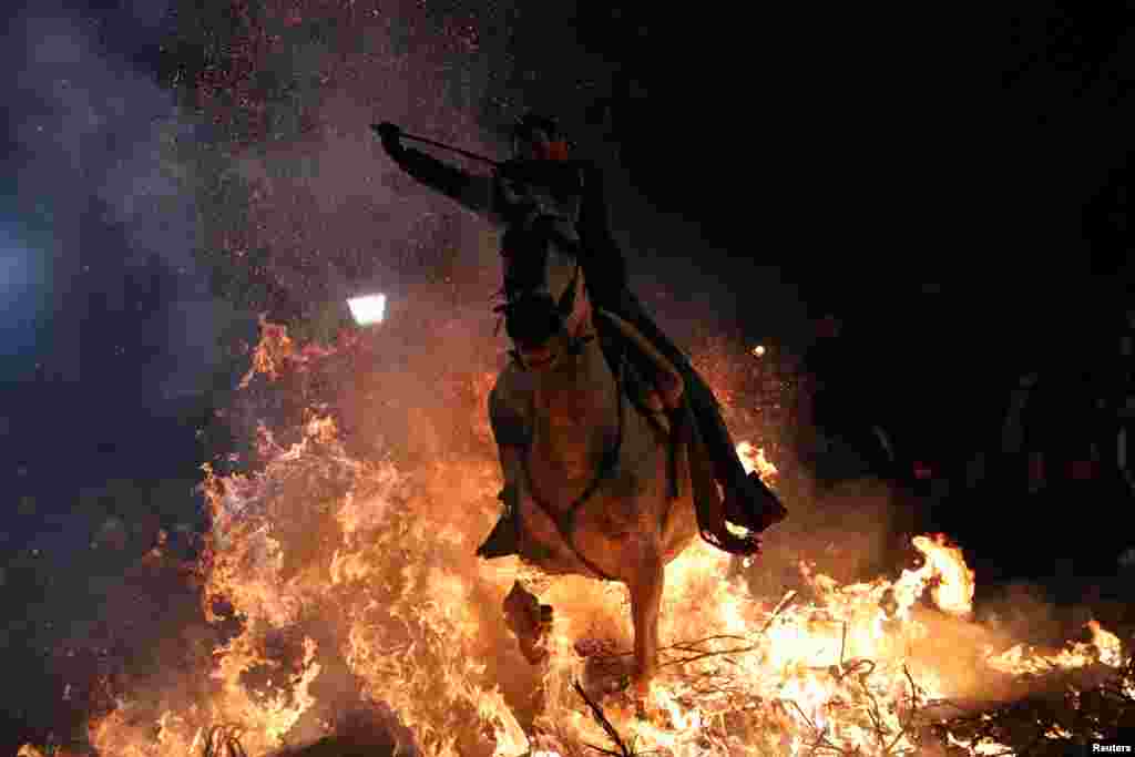 A woman rides a horse through flames during the annual &quot;Luminarias&quot; celebration on the eve of Saint Anthony&#39;s day, Spain&#39;s patron saint of animals, in the village of San Bartolome de Pinares, northwest of Madrid, Jan. 16, 2019.