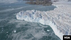 A rising plume of sediment-laden subglacial meltwater discharge protrudes into the water surface, as seen in the massive calving front of the southernmost of four tributaries of Upernavik Icestream, Greenland. [Natural History Museum of Denmark - N.J. Kor