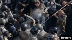 Radical protesters, including supporters of the All-Ukrainian Union Svoboda (Freedom) Party, clash with law enforcement members during a rally near the parliament building in Kyiv, October 14, 2014.